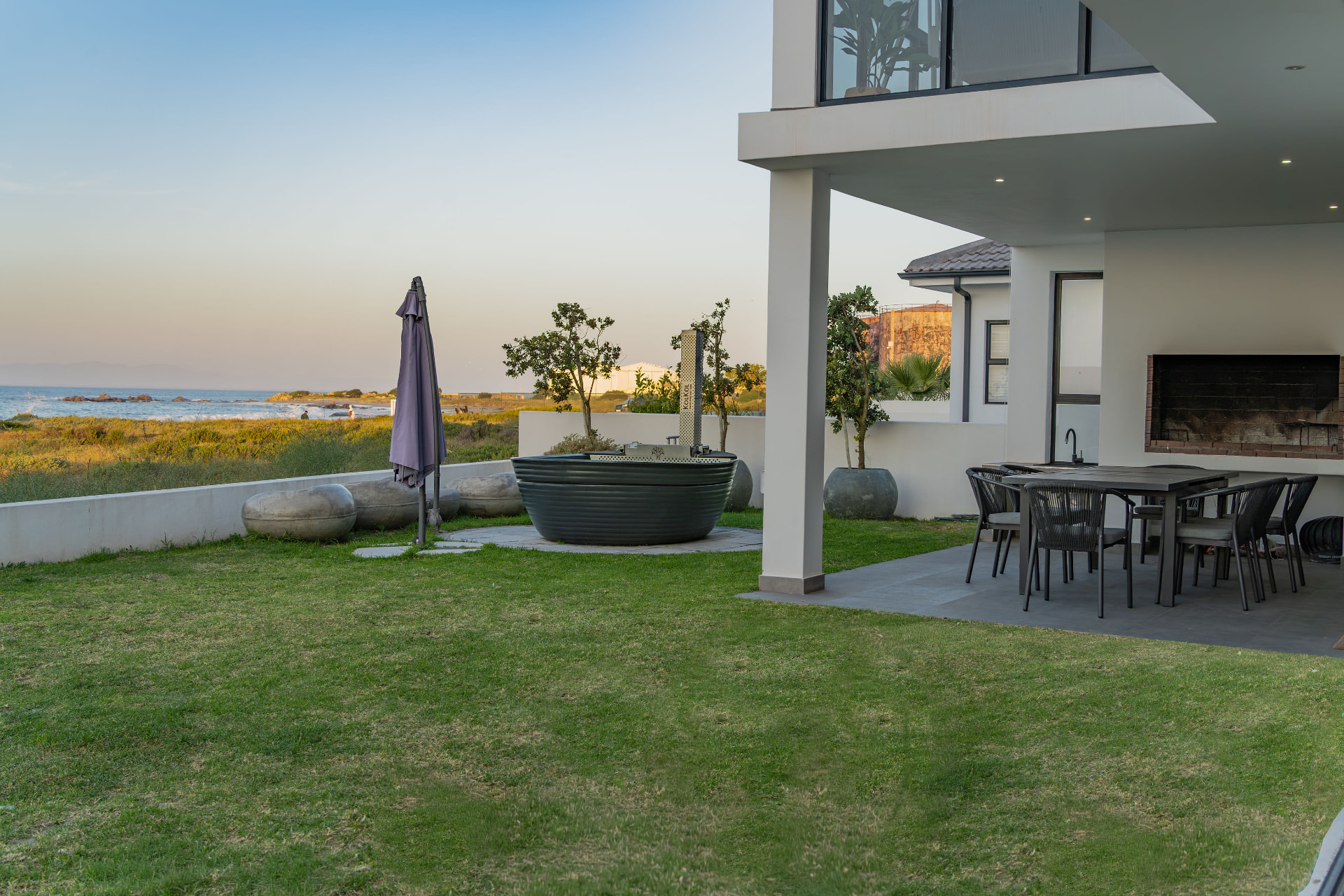 Covered patio with braai fireplace and dining table facing the sea