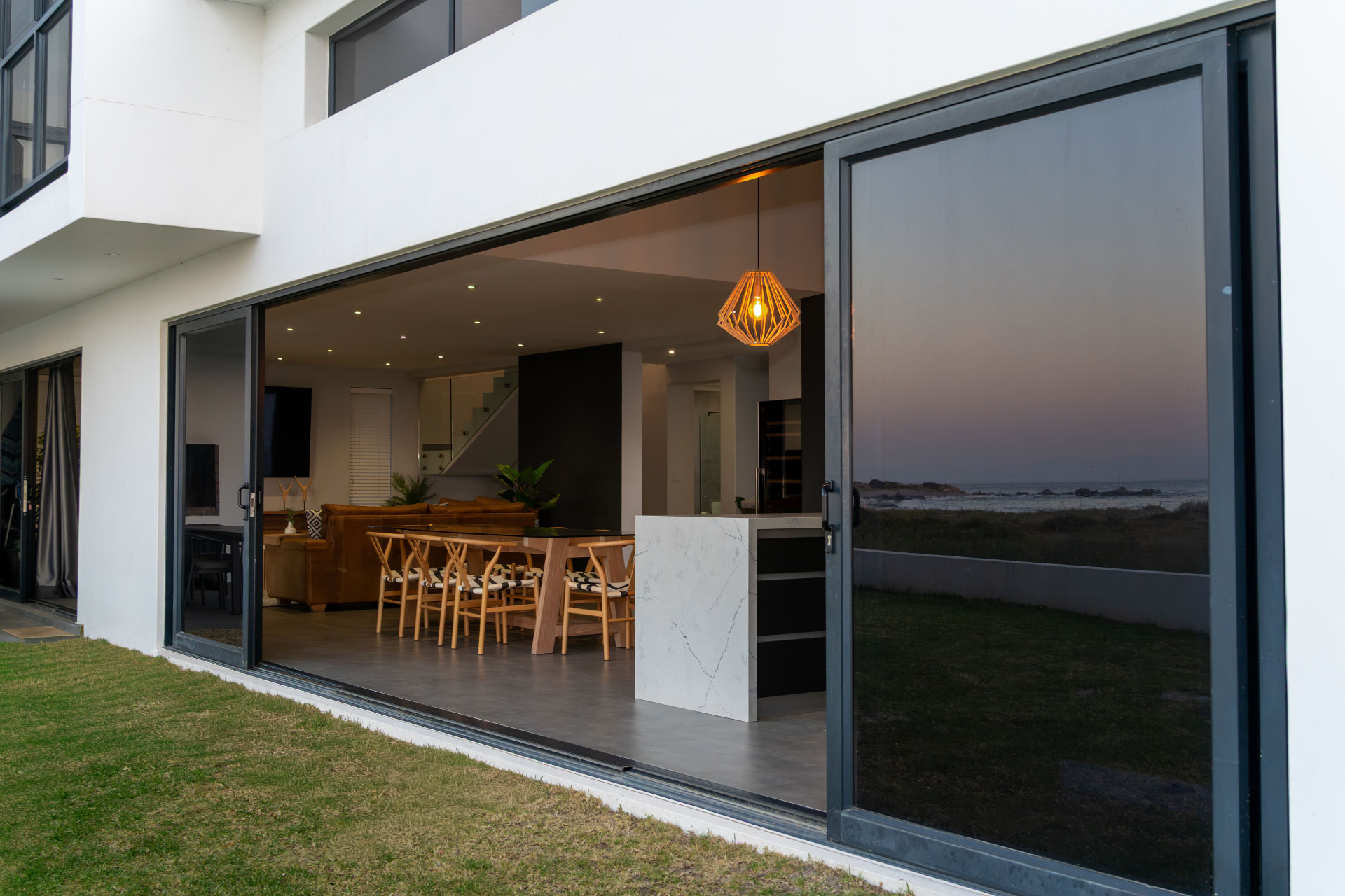 Open-plan living and dining room opening to the lawn and sea